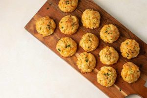 An overhead view of Cheddar Biscuits on a wooden platter.