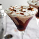 Two Chocolate cream martinis in martini glasses with a shaker to the left if them.