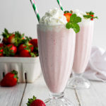 Two boozy strawberry milkshake with a straw in each of them.