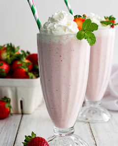 Two boozy strawberry milkshake with a straw in each of them.