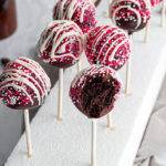 an overhead view of two rows of decorated cake pops with a bit taken out of one.