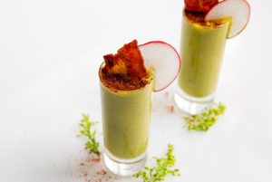 An over view of two pea shooters in a shot glass with bacon in them