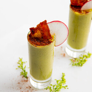 An over view of two pea shooters in a shot glass with bacon in them