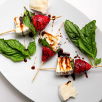 Three strawberry, basil, and brie bites on a white plate