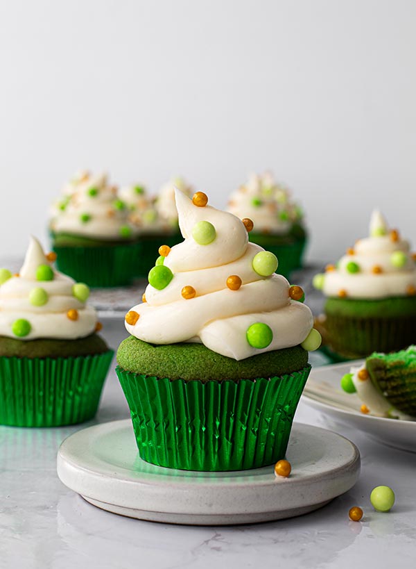Green Velvet cupcake decorated with sprinkles on a white stand.