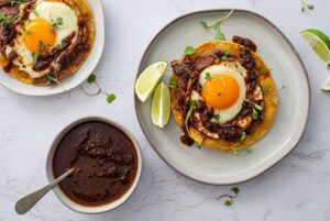 A white plate of Salsa Macha Breakfast Tostadas with a fried egg on top.