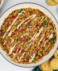 he Warm Cannellini Bean dip on a white platter with bread next to it.